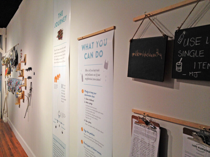 wall with hanging banners, clipboards with petitions, and chalkboards to right personal pledges